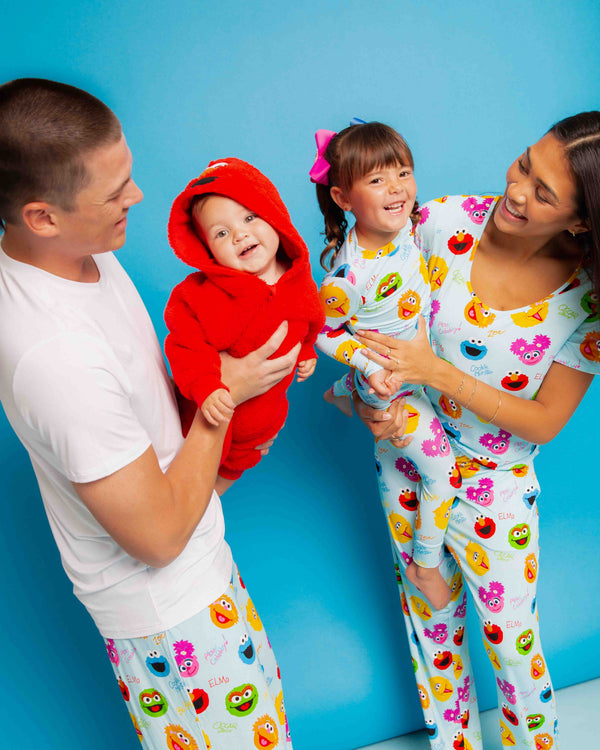 Family wearing Sesame Street pajamas with ELMo, Cookie Monster, Oscar and Abby Cadabby prints; baby in ELMo hood