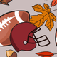 A maroon football helmet surrounded by autumn leaves and acorns.